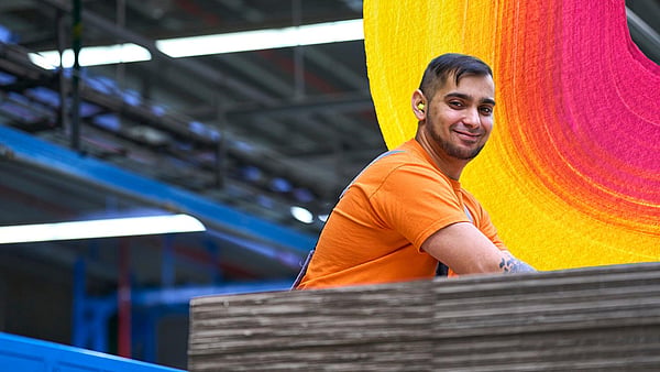 man in orange t-shirt at work in a factory setting
